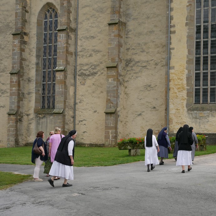 Auf dem Foto sieht man Ordensleute, die auf dem Weg zur Kirche sind.

Foto: LWL (öffnet vergrößerte Bildansicht)