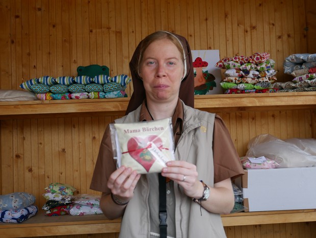 Auf dem Foto sieht man eine Schwester, die in der Klostermarkthütte ein Kissen präsentiert.

Foto: LWL